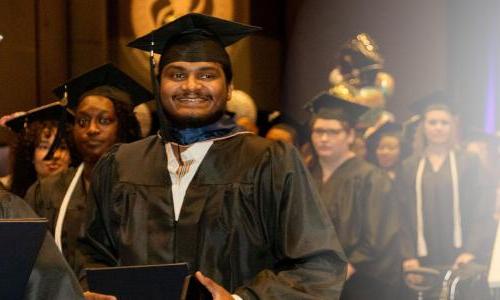 Herzing大学 online 工商管理硕士 graduate smiling while walking to receive his degree 